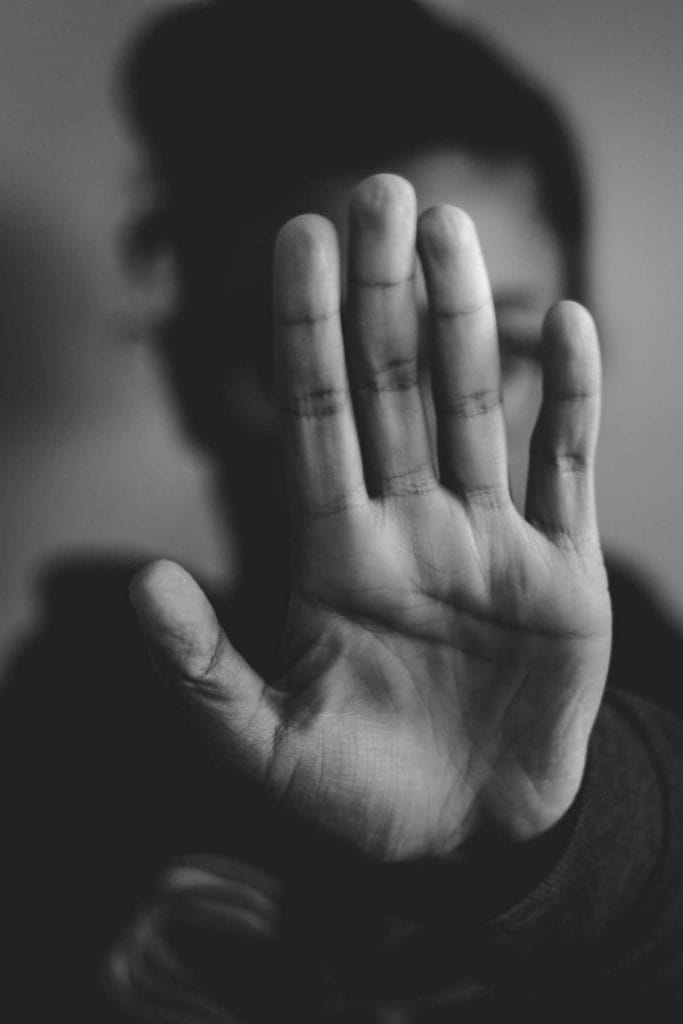 woman in black and white with hand in front of face