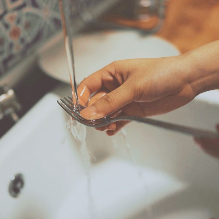 hand washing a fork in the sink