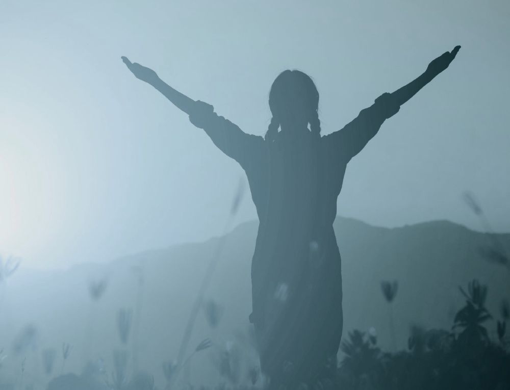 girl with arms open on a hilltop